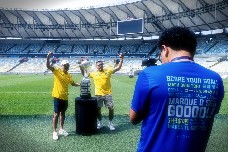 Visitantes posando com a taça no gramado do Maracanã enquanto são filmados.